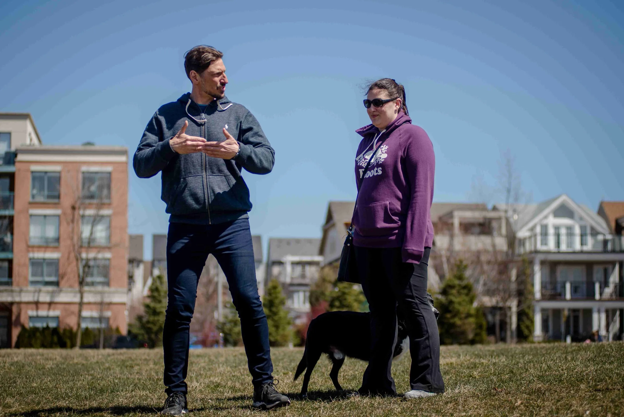 Mark talking a client through her dog's behaviour in a Toronto park, the dog calm at their feet